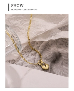 Macro view of gold Figaro chain featuring a polished heart padlock pendant detail