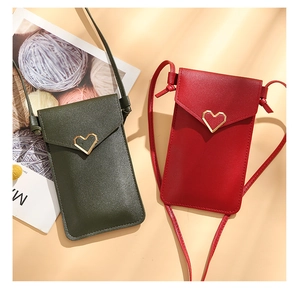 Detail of crossbody phone bags in dark green and red with golden heart buckles