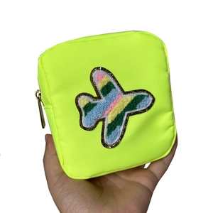 Neon green nylon cosmetic bag with colorful airplane patch and gold zipper detail