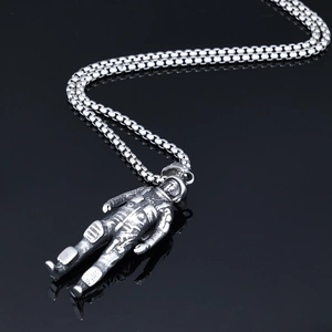 Detail of vintage silver astronaut pendant necklace on reflective black surface