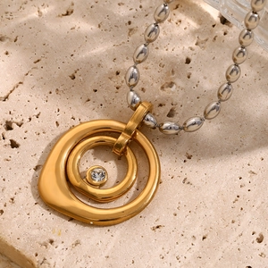 Close-up of 18K gold-plated double ring pendant with zircon on a silver bead chain