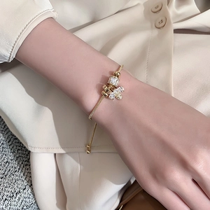 Detail of a golden snake chain bracelet with zircon-encrusted beads and a bee pendant