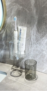 Detail view of wall-mounted PET toothbrush holder with transparent rinse cups on marble wall