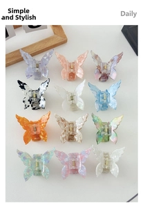 Flat lay of twelve assorted acetate butterfly hair claws in various marble and pearl colors