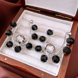 Detail view of silver C-shaped earrings with black faceted beads on a jewelry display