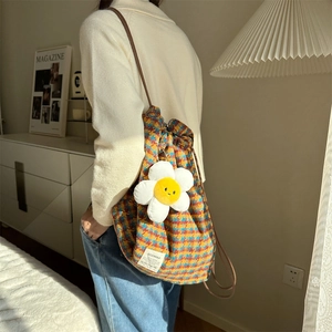 Detailed shot of check pattern backpack featuring a white plush flower charm accessory