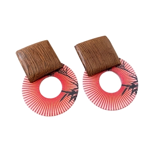 Ethnic wood earrings with red radial pattern and black bamboo silhouette on white background