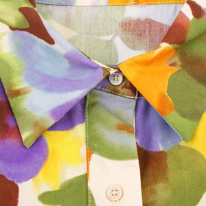 Détail macro du col de chemise avec imprimé floral coloré et boutons blancs ronds