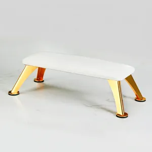 Close-up of white leather manicure footrest with polished gold metal legs and non-slip pads