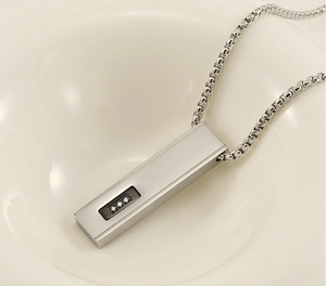 Detail of silver rectangle bar pendant with black groove and three clear zircons on chain