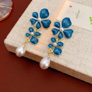 Detail of vintage blue enamel flower earrings with large white teardrop pearls and gold trim