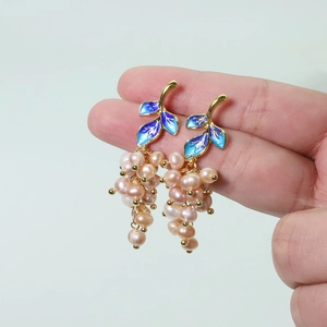 Detail of leaf design and pink freshwater pearl cluster earrings in golden finish