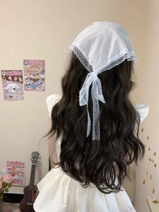Détail d'un foulard triangle blanc à pois avec bordure en dentelle sur cheveux