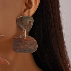 Close-up of model wearing green marble resin earrings with irregular geometric shapes