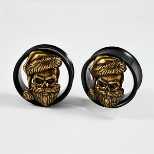 Detail of black hollow ear gauges with golden skull wearing a Christmas hat relief
