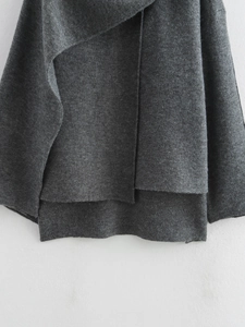 Dettaglio dell'orlo asimmetrico del cardigan a maglia grigio scuro modello poncho