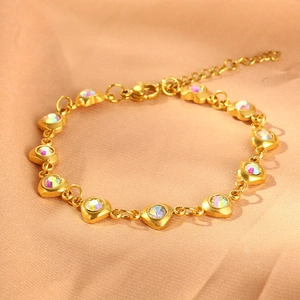 Detail of gold heart-shaped stainless steel bracelet with iridescent stones on pink silk