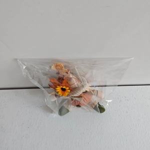 Close-up of Thanksgiving scarecrow doll with maple leaf and sunflower details in packaging