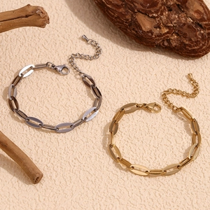 Détail de bracelets à maillons dorés et argentés avec chaînettes réglables sur fond texturé