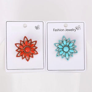 Detailed view of orange and turquoise beaded flower brooches on fashion jewelry cards