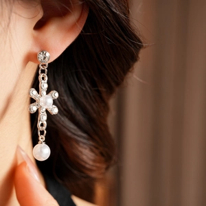 Detail of silver drop earrings with crystal cross and two white pearls on model