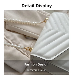 Detail of white V-quilted leather crossbody bag with elegant pearl strap and gold hardware