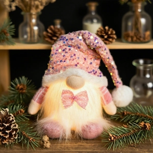 Pink glowing Christmas gnome plush with sequins and fur on a wooden shelf setting