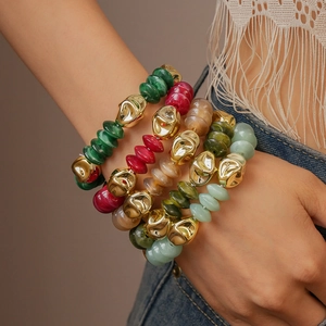 Stacked bohemian acrylic beaded bracelets in gold and mixed colors on woman's wrist