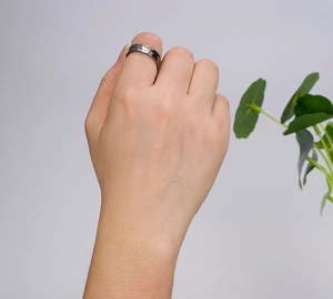 Close-up of a men's gunmetal copper ring with a hammered matte finish on a finger