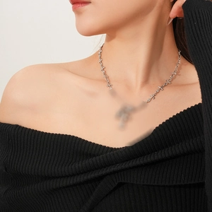 Detailed view of a silver pin necklace with cross pendants on a model's neck