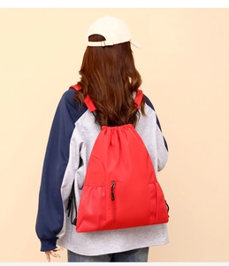 Nahaufnahme des roten Oxford-Gewebe Kordelzug-Rucksacks mit Front-Reißverschlusstasche.