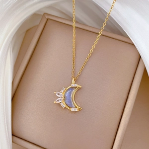 Luxurious gold moon pendant necklace with crystals on beige box with white silk background