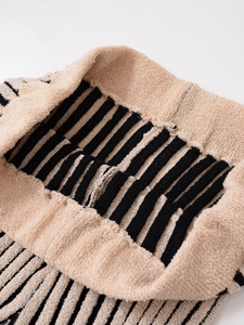 Macro detail of elastic waistband on beige and black striped knit pants with soft texture