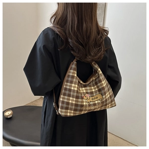 Detail of checkered shoulder bag with dog embroidery shown on model back