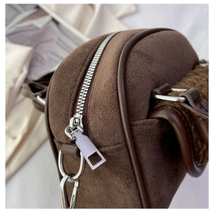 Close-up of dark brown suede texture and premium silver metal zipper on stylish handbag