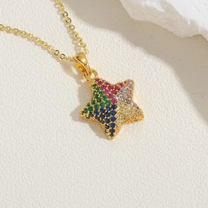 Macro shot of gold star pendant inlaid with colorful zircon stones on white marble