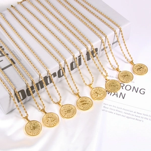 Detailed view of multiple 18K gold zodiac coin pendants on twist chains over white silk