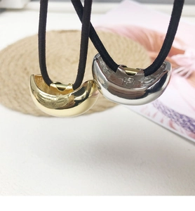 Detail of gold and silver U-shaped metal charms on black high-elastic hair ties