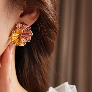 Detail of vintage flower earring with orange enamel glaze and sparkling crystals