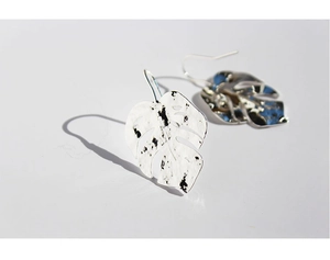 Detailed view of silver Monstera leaf earrings with elegant shadows on a white background