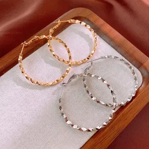 Irregular textured gold and silver circular hoop earrings with diamond-cut metal finish