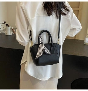 Detail of black lychee grain bucket bag with decorative scarf and gold hardware