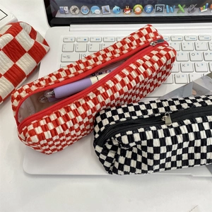 Macro detail of checkered quilted velvet pencil case and smooth metal zipper closure