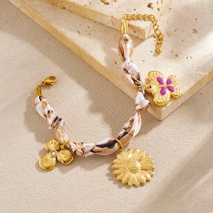 Bracelet doré avec papillon, fleur et ruban léopard posé sur une pierre naturelle