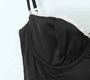 Gros plan d'une robe en satin noir avec bordure en dentelle blanche et fines bretelles