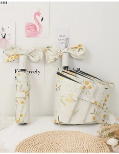 Close-up of cream umbrella with yellow floral pattern and unique bow handle design