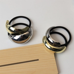 Close-up of gold and silver metallic curved charms on high-elasticity black hair ties