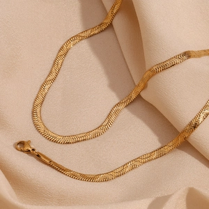 Macro detail of 18K gold plated herringbone chain on elegant beige satin fabric