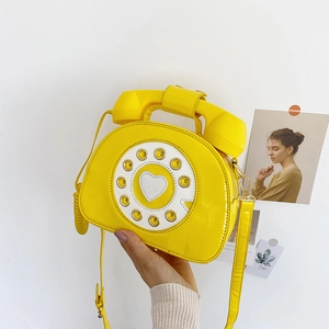 Detail of yellow patent leather handbag in a vintage rotary telephone creative shape