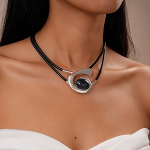 Close-up of a silver spiral necklace with a black stone on a layered cord worn by a model